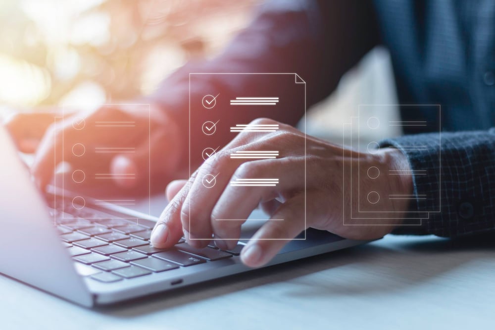 A person types on a laptop behind a translucent graphic of a list.