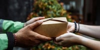 Hands passing a delivery box, representing seamless omnichannel fulfillment strategies.